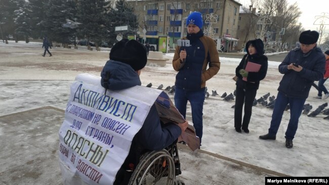Эрик Жумабаев с плакатом на площади.