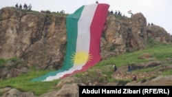 An Kurdish flag is unfurled during Nowruz celebrations in Aqra/Akre, Arbil