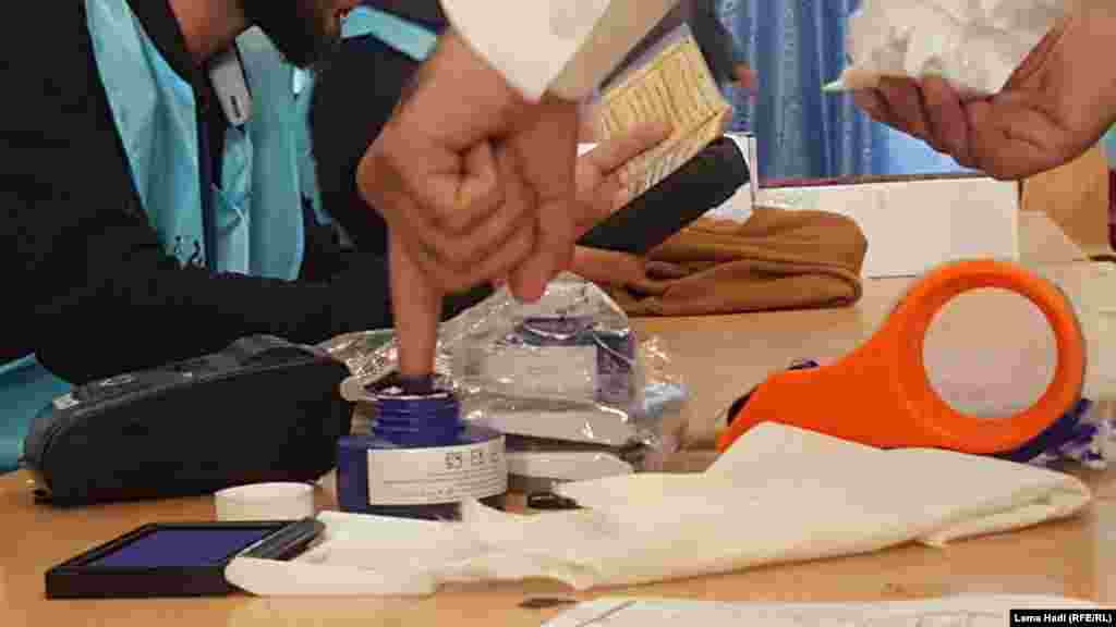 کارمند موظف کمیسیون انتخابات انگشت یک رأی دهنده را با رنگ مخصوص رنگ می&zwnj;کند.