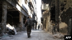 Men walk past destroyed buildings in the Yarmouk Palestinian refugee camp in the Syrian capital, Damascus, on April 6. 