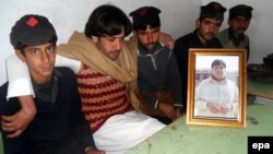 Mujtaba Hasan (second from left) with a picture of his brother of Atizaz, who reportedly sacrificed his life to stop a suicide bomber outside his school. 