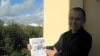 Аляксандар Лукашук на гаўбцы менскай кватэры Освальда зь ягоным здымкам. Архіўнае фота