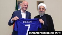 Iranian President Hassan Rohani (right) and FIFA President Gianni Infantino hold up a soccer shirt with Rohani's name during Infantino's visit to Tehran in March 2018.