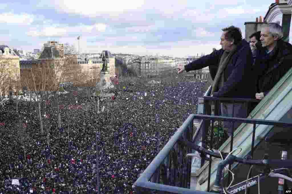 Residents watch from a balcony above the Place de la Republique in Paris.