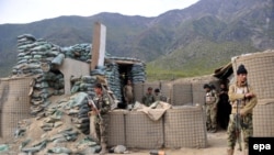 FILE: Afghan soldiers inspect their checkpost damaged in a militant attack in Kunar.