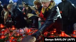 A man lays black bread and lit candles during a commemoration ceremony at a monument in Kyiv to victims of the Holodomor famine of 1932-33.