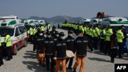 Спасатели несут тело погибшего при крушении парома в Южной Корее. 20 апреля 2014 года