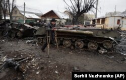 Чоловік на милицях проходить повз знищену українськими військами російську військову техніку у Бучі під Києвом. 1 березня 2022 року