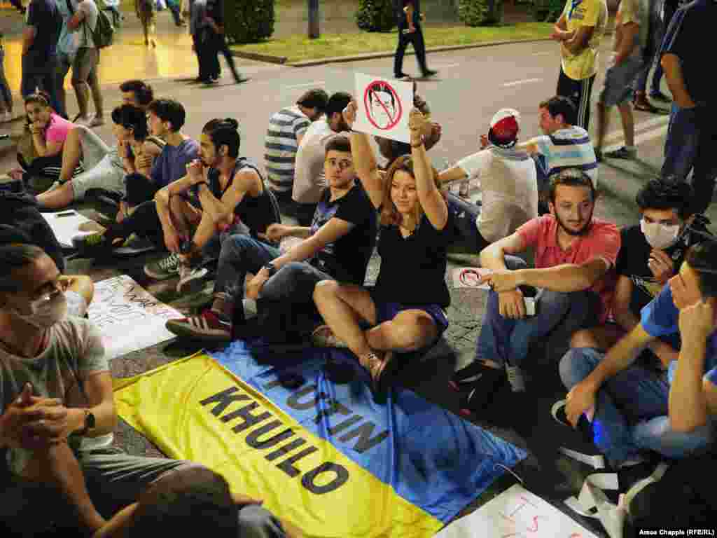 Protesters display an anti-Putin slogan on a Ukrainian flag. Mariam Basharuli, holding a picture of Bidzina Ivanishvili, said the protesters are demanding the release of those detained during the first night of unrest. "We will stay here until our boys are released. So many of our friends were taken,” she said.