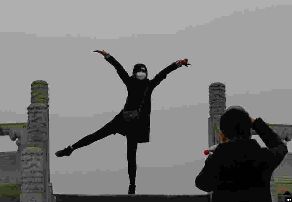 A woman wearing a protective mask in smog poses for photos at the Temple of Heaven Park in Beijing. (epa/Rolex Dela Pena)