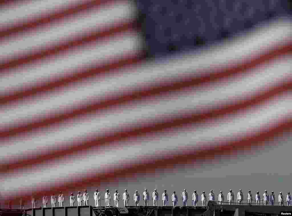 Crew members of the USS Ronald Reagan, a Nimitz-class nuclear-powered aircraft carrier, are seen behind the U.S. flag as the ship arrives at the U.S. naval base in Yokosuka, south of Tokyo. (Reuters/Yuya Shino)