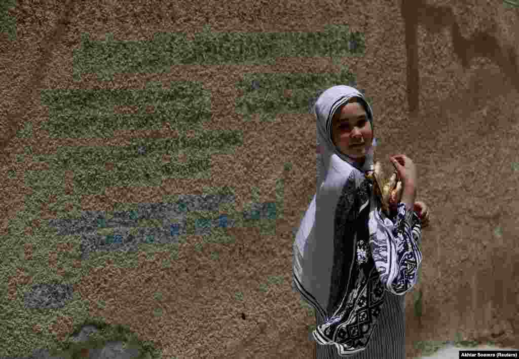 A Hazara girl walks holding naans (breads) along a street in Hazara Town, Quetta, Pakistan, June 13, 2019.