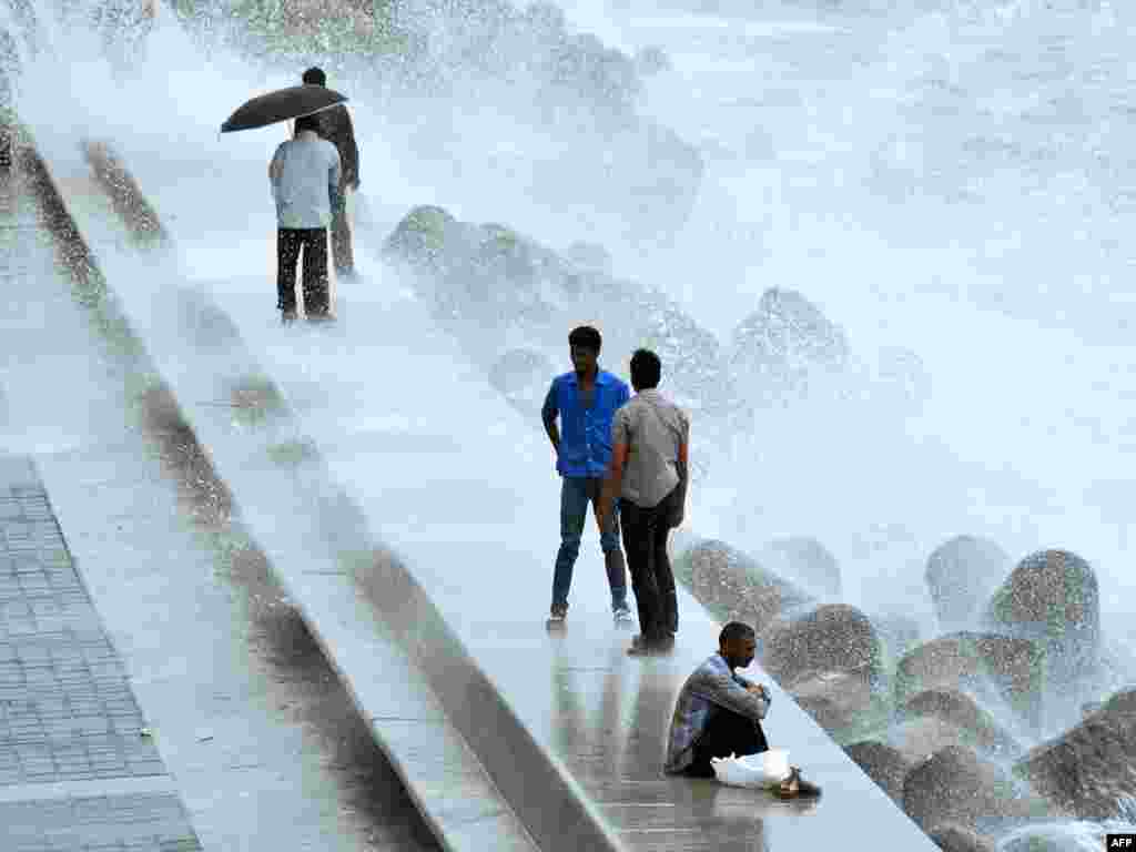 Indian pedestrians walk along the coast in Mumbai during the height of the monsoon. Photo by Punit Paranjpe for AFP