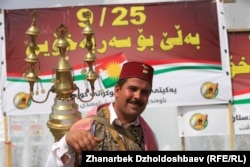 A Kurdish man stands in front of a poster promoting the Kurdish referendum.