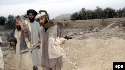 Afghan men show shrapnel from missiles that struck their village in the U.S.-led air strike in Farah Province.