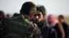 A fighter from Syrian Democratic Forces (SDF) checks a man near the village of Baghouz on February 22. 