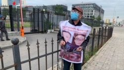 Житель Алматы Женис Заркын с плакатом с фото своих родственников приковал себя к ограде у посольства Китая. Нур-Султан, 26 июня 2020 года.