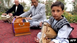 A young boy in Kabul plays a rabab, a traditional musical instrument.