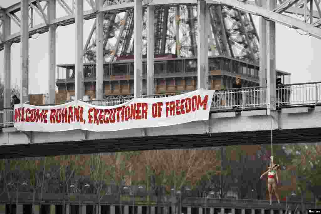 A topless Femen activist hangs from a bridge as the women&#39;s rights group stages a protest against Iranian President Hassan Rohani&#39;s visit to Paris on January 28. (Reuters/Charles Platiau)