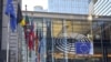 Sign and EU flags on glass walls of Berlaymont, that houses the headquarters of the European Commission, which is the executive of the European Union.