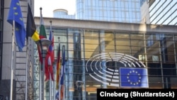 Sign and EU flags on glass walls of Berlaymont, that houses the headquarters of the European Commission, which is the executive of the European Union.