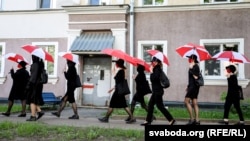 Женщины с красно-белыми зонтами в Минске во время флешмоба. Сочетание этих цветов стало де-факто запрещенным в Беларуси после протестов, на которых оппозиция использовала исторический бело-красно-белый флаг 