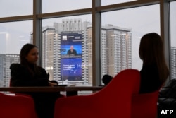 Un ecran gigant care transmite o conferință de presă a președintelui rus Vladimir Putin este vizibil pe fațada unui bloc din Moscova.
