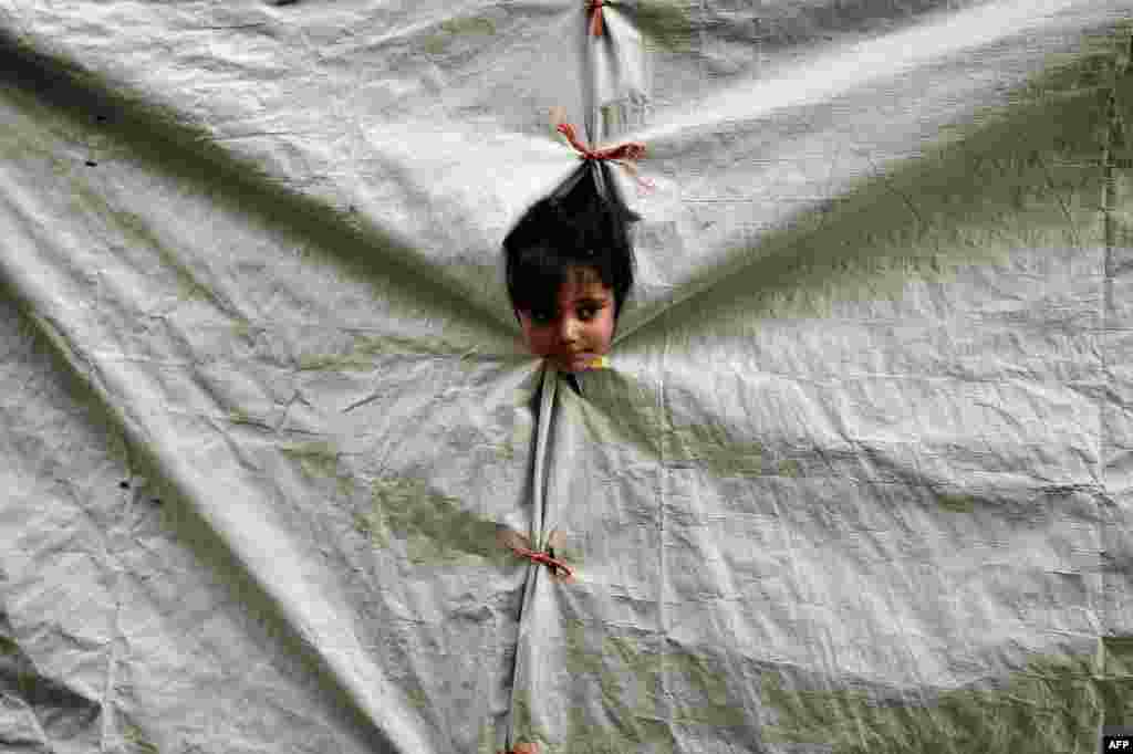 A child peers out of her tent at a refugee camp on the Greek island of Chios. (AFP/Louisa Goulimaki)