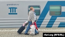 Пассажиры на фоне поезда «Таврия» российского оператора «Гранд сервис экспресс». Крым, 25 апреля 2024 года