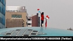 An image taken from social media shows a woman staging a public protest against Iran's strict dress code in Tehran on October 29. 