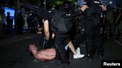 Policijski službenici privode demonstranta nakon protesta u Beogradu, Srbija, 28. juna 2025.