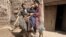 Afghanistan -- A health worker (L) administers polio vaccine to a child (C), seen sitting on a donkey, on the third day of a vaccination campaign in Herat, 27Mar2012