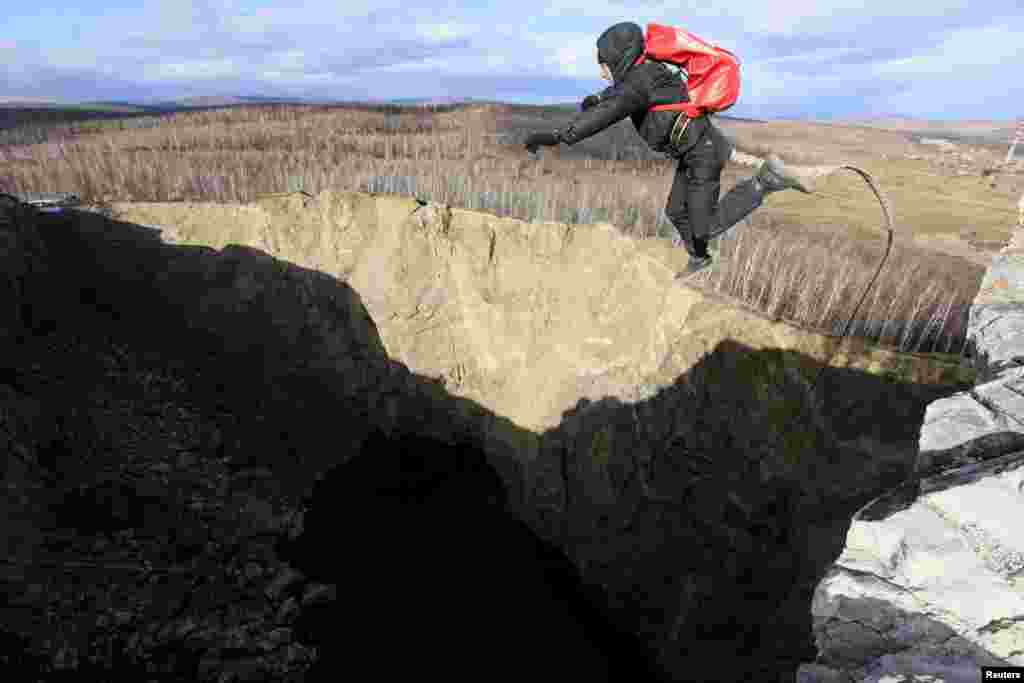 A member of the "Exit Point" amateur rope-jumping group jumps from a 120-meter rock down to a man-made crater called Tuimsky Proval, near the Russian town of Tuim on October 20. (Reuters/Ilya Naymushin)