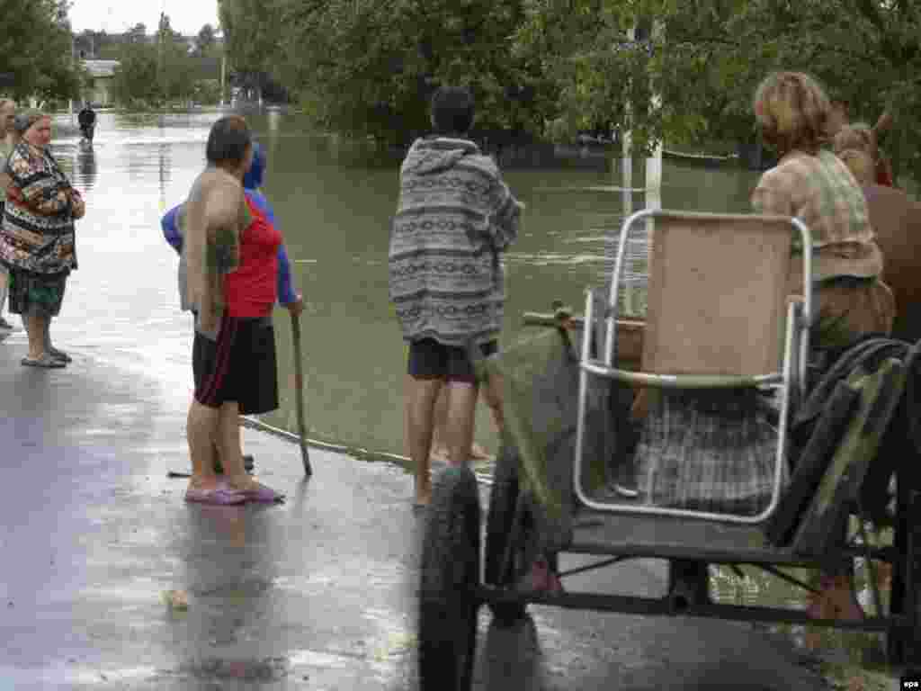 epa01426576 People look at the water after massive flooding in Drepcauti, 270 km north of Kishinev, Moldova, 29 July 2008. Six persons died and hundreds were evacuated after the increase of Prut river floodplain. The amount of water in the river Prut increased after heavy rains in the Ukraine and Romania. EPA/STR 