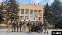 Ukrainian soldiers pose in front of the Lyman administration office on October 1.