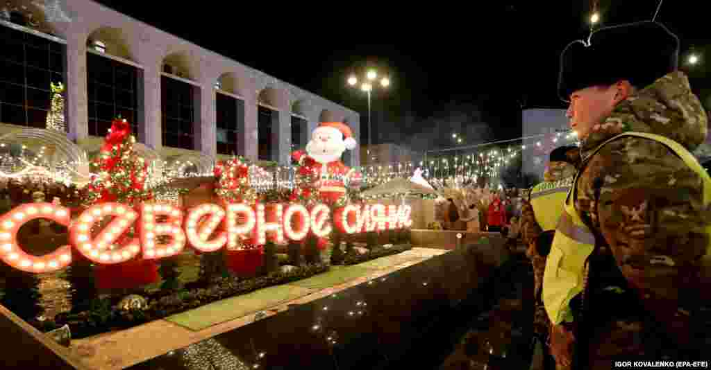 Kyrgyz soldiers stand guard as people gather in front of an illuminated Christmas tree and other decorations on the central Ala-Too Square in Bishkek.&nbsp;