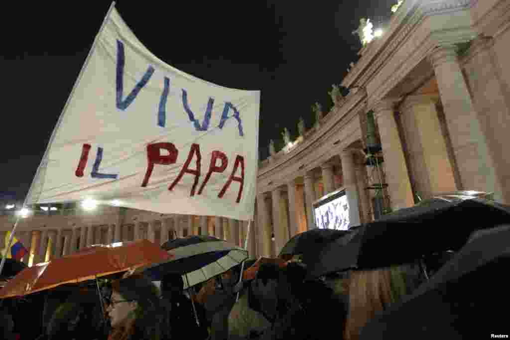 People cheer as white smoke rises from the chimney above the Sistine Chapel.