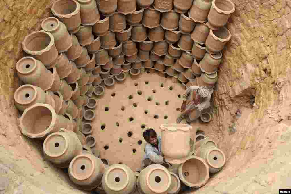Рабочие расставляют глиняные горшки в печи, чтобы запечь их перед тем, как выставить на продажу, фабрика в Пешаваре, Пакистан, 2 июля 2025 года. REUTERS/Fayaz Aziz 