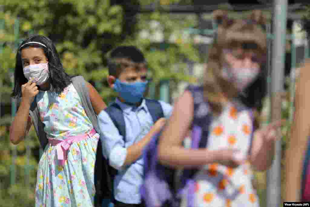 Alegra Bajrami (left), wearing a face mask to protect against the coronavirus, enters a schoolyard on the first day of the new academic year in Kosovo&#39;s capital, Pristina. Kosovar schools reopened on September 14 for the first time since March when the COVID-19 crisis began.