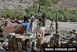 Taliban fighters stand next to a cache of ammunition along a road in the Bazark district of Panjshir Province in September 2021, days after the militants announced the capture of the last province resisting their rule.