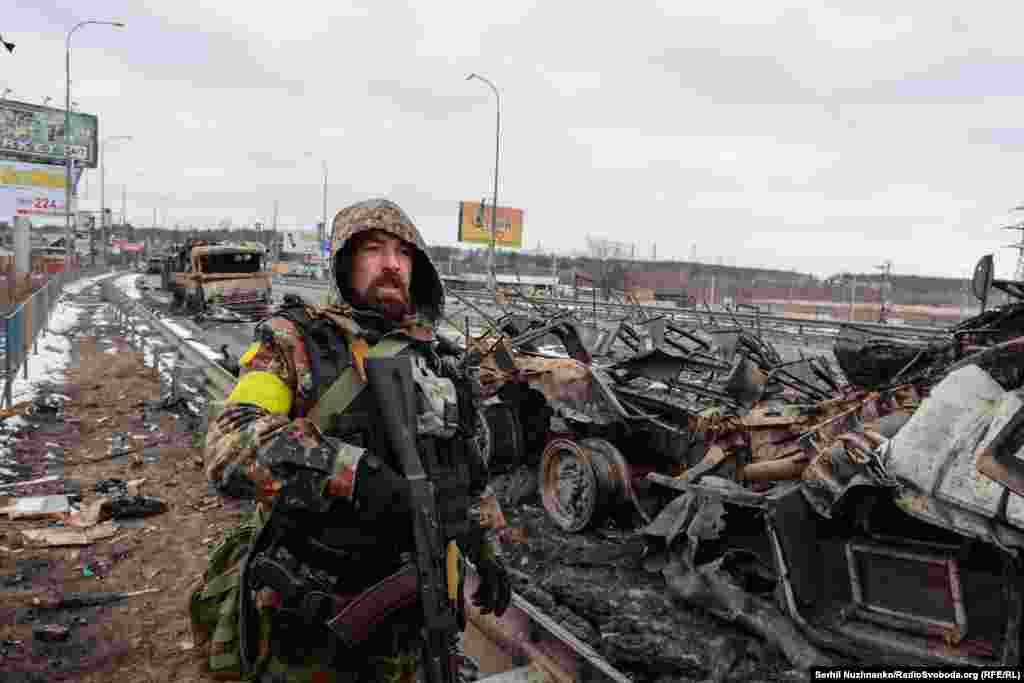 1 березня 2022 року. Військовий ЗСУ дивиться на рух на іншій стороні Гостомельського мосту на Київщині. Стоячи біля знищеної колони російського ОМОНу, яка проривалася до столиці, він звернувся до матерів солдатів РФ: «Подивіться, якщо приїдуть ваші чоловіки до нас, матері, подивіться на них. Навіщо ви їх сюди пускаєте? Ми їх покладемо, усі колони, але Україну ми не здамо»