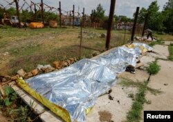 Изгорените тела на убитите при взрива в Еленовка са наредени на земята и покрити с найлон.