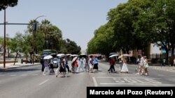 Turisti se sa kišobranima štite od sunca u Sevilji, 29. juna 2025.