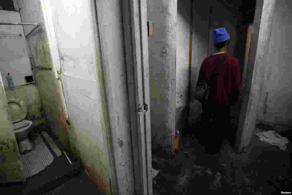 Ng, a 60-year-old man, leaves a communal toilet near his 5.6-square-meter subdivided flat inside an industrial building in Hong Kong. (2012 photo)