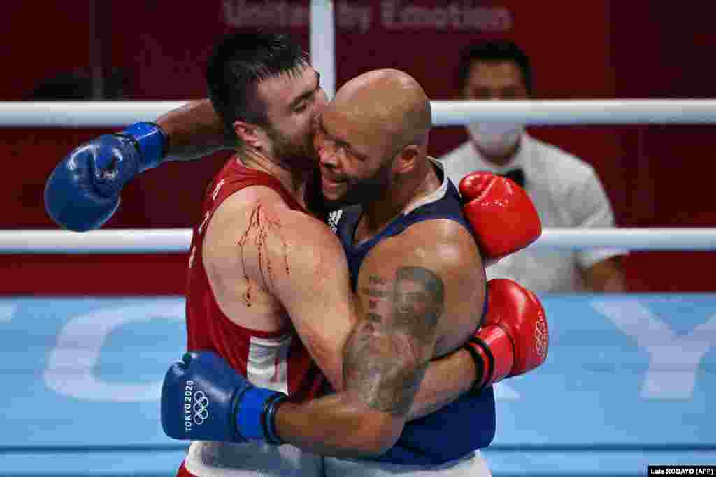 Uzbekistan's Bakhodir Jalolov (red) and Britain's Frazer Clarke hug after their men's super heavy (over 91kg) semi-final boxing match during the Tokyo 2020 Olympic Games at the Kokugikan Arena in Tokyo on August 4, 2021.