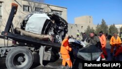 Afghan security personnel and municipality workers remove a damaged vehicle after a roadside bomb in Kabul on December 22.