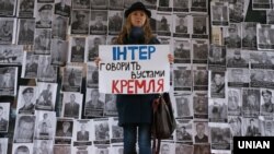 Громадська активістка під час акції протесту біля офісу телеканалу «Інтер» на тлі фотографій українських воїнів, які загинули на Донбасі у війні України проти Росії. Київ, 11 грудня 2014 року