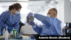 آرشیف، یک داکتر در حال آزمایش واکسین ضد ویروس کرونا