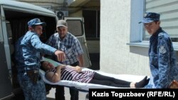 Конвоиры вытаскивают из автомобиля носилки с лежачей больной заключенной Гаухар Худабаевой. Алматинская область, 20 июня 2019 года. 