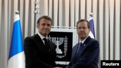 Presidenti i Francës, Emmanuel Macron (majtas) shtrëngon duart me presidentin e Izraelit, Isaac Herzog, gjatë vizitës në Izrael më 24 tetor 2023.